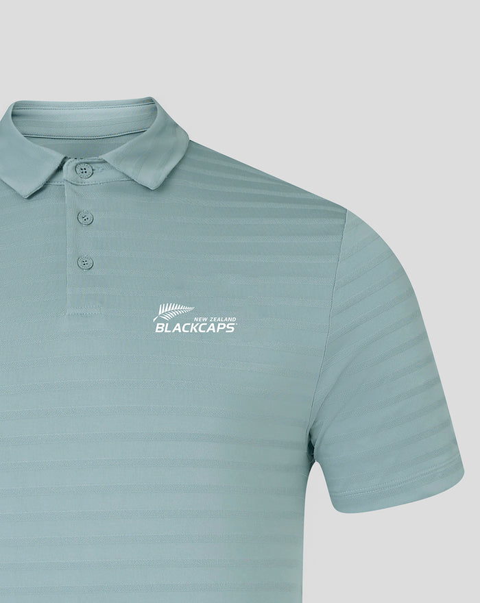 Light blue NZC Club Essential golf polo with subtle horizontal stripes and a white BlackCaps logo on the chest