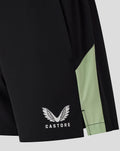 Close up of the lower leg of black shorts showing the Castore logo and lime green trim