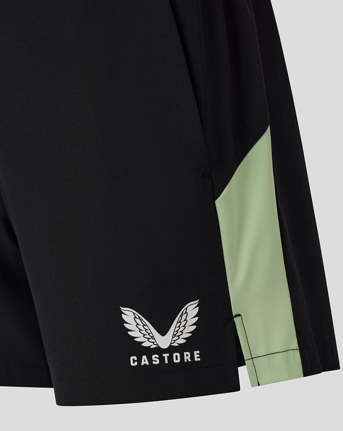 Close up of the lower leg of black shorts showing the Castore logo and lime green trim