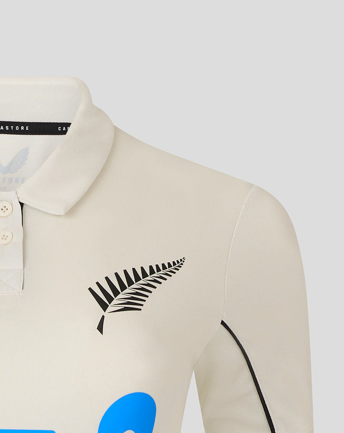 Cream polo shirt with a black fern wing logo on the left chest and light button placket