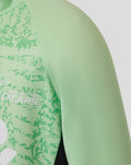 Shoulder close up of mint green junior training midlayer top with fern pattern across the front