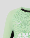 Close up of a mint green junior training T shirt with a leafy front pattern and white chest logo.