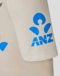Close-up of the beige Junior 25/26 Test Short Sleeve Shirt sleeve with a bright blue ANZ logo