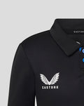 Close up of the upper front of a black junior T20 polo showing the Castore wing logo on the chest and blue button placket