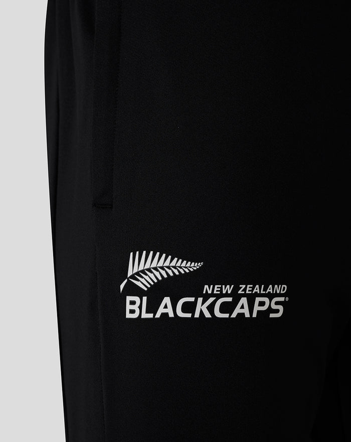 Close-up of black pant leg with large white BLACKCAPS logo and fern leaf graphic.