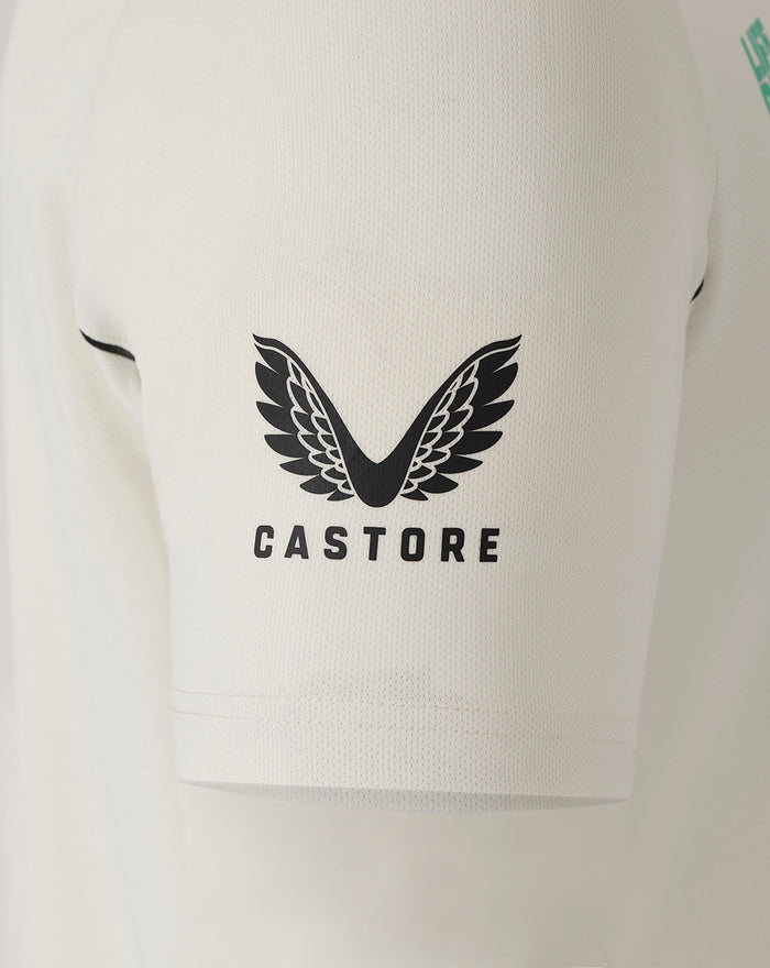 Close-up of cream polo sleeve with blue ANZ logo and Castore wing branding visible on the chest area.
