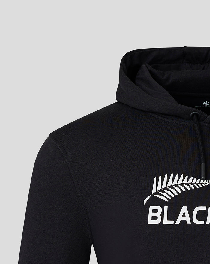 Close-up of the chest area showing the white BlackCaps logo and fern graphic on the black hoodie.