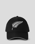 Close up of black ODI playing cap showing crown top button and white embroidered fern design across the crown