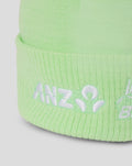Close-up of the lime green knit hat showing white embroidered branding along the cuff